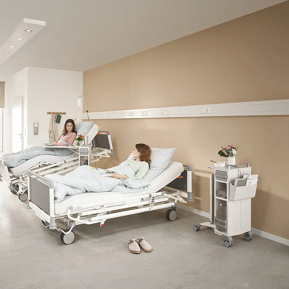 Evario one Klinikbetten mit Quado Nachttisch für effiziente Raumnutzung im Patientenzimmer.