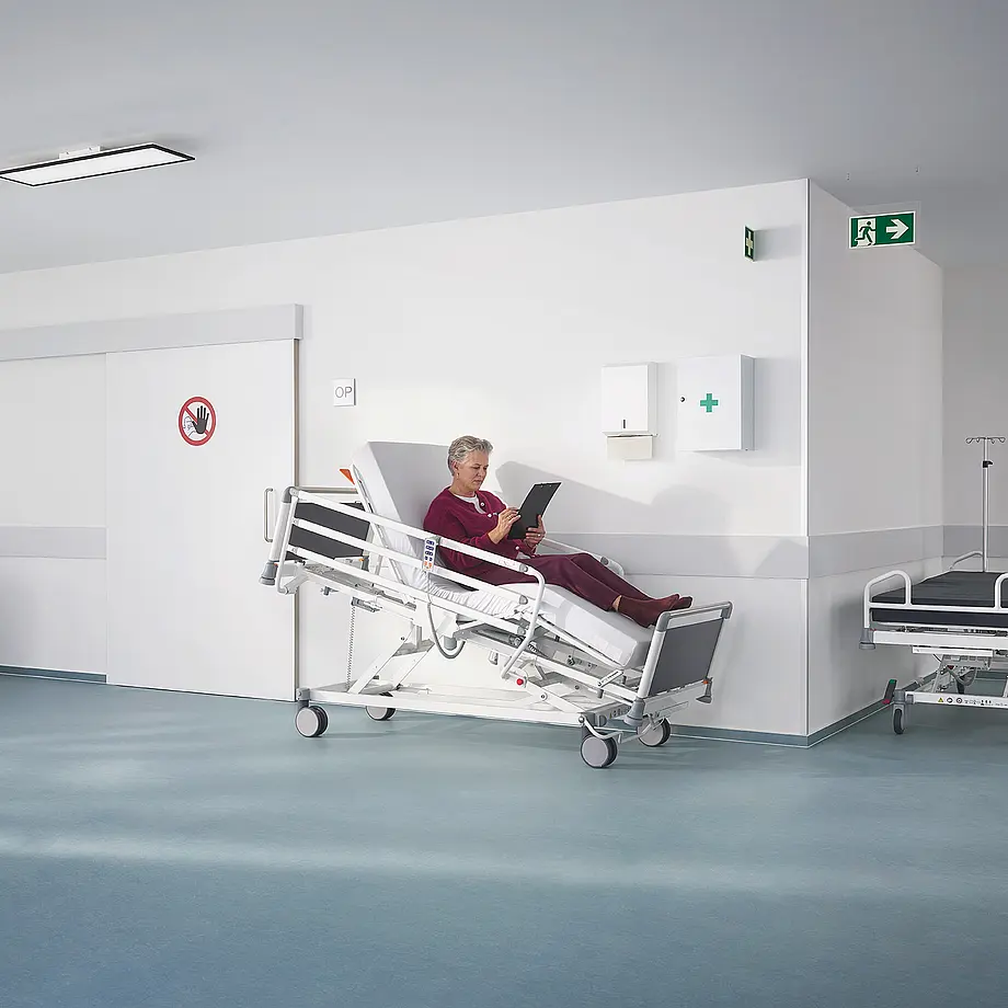 Evario one Patientenliege mit platzsparender Seitensicherung für sichere Versorgung im Klinikalltag.