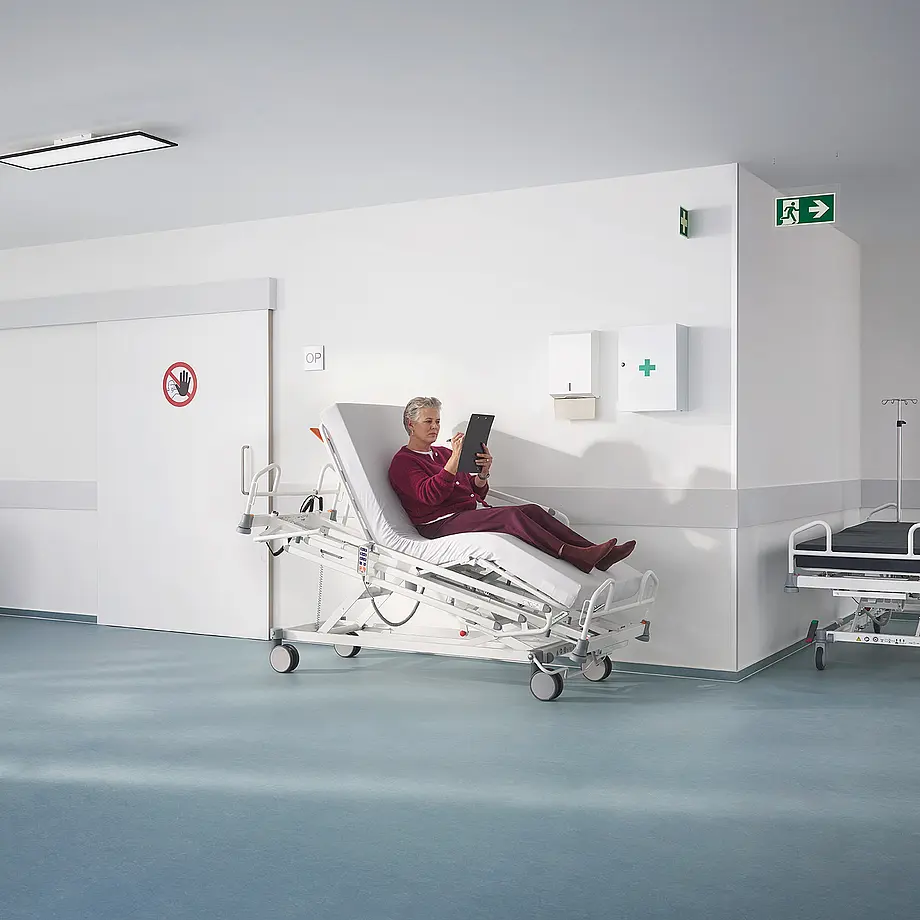 Patientin in der Herzstuhlposition im Evario one Pflegebett im Klinikbereich.